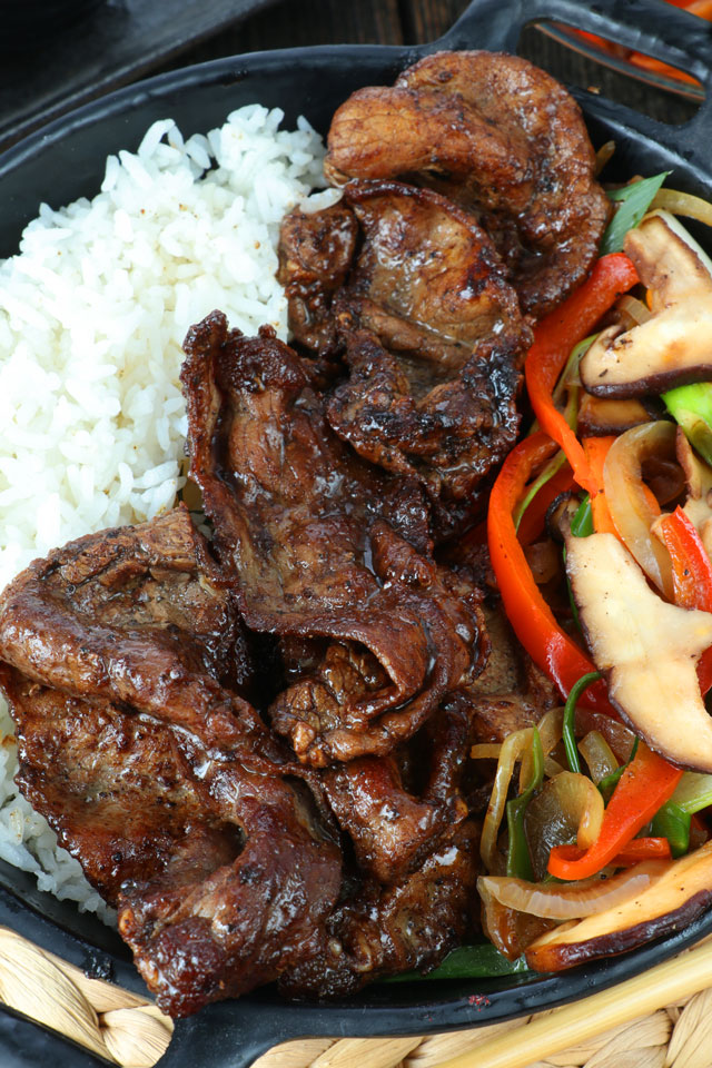 Cooked thin cuts of beef sirloin with rice and vegetables on side.