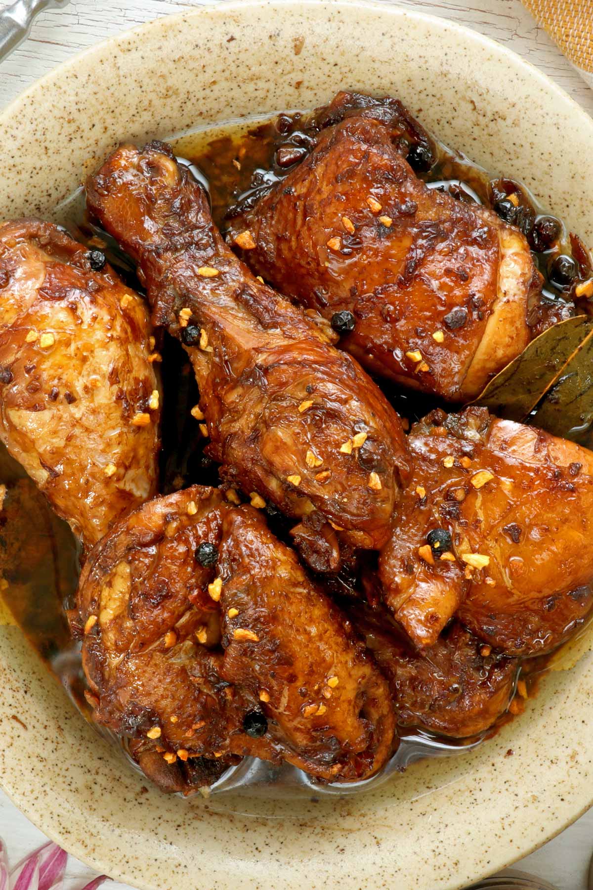 Chicken cooked in soy sauce and vinegar with peppercorns, bay leaves, onions.