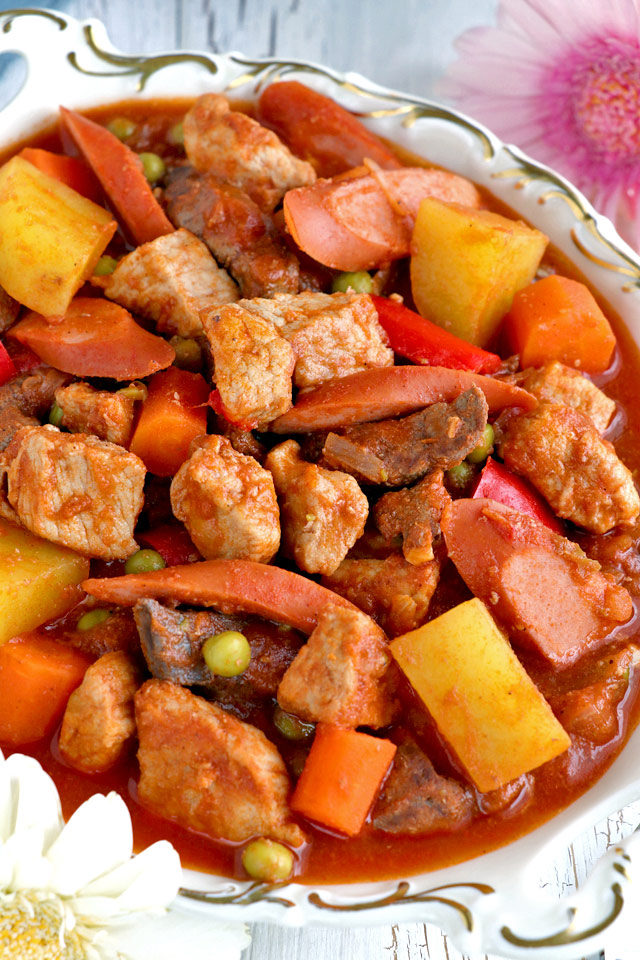 Filipino tomato-based pork stew with meat, liver, potatoes, carrots, hotdogs, and green peas