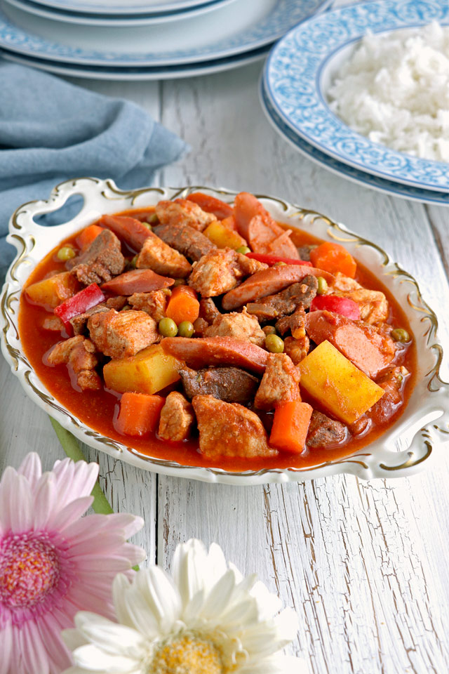 A tomato based pork stew with pork meat, liver, carrots, potatoes and green peas.