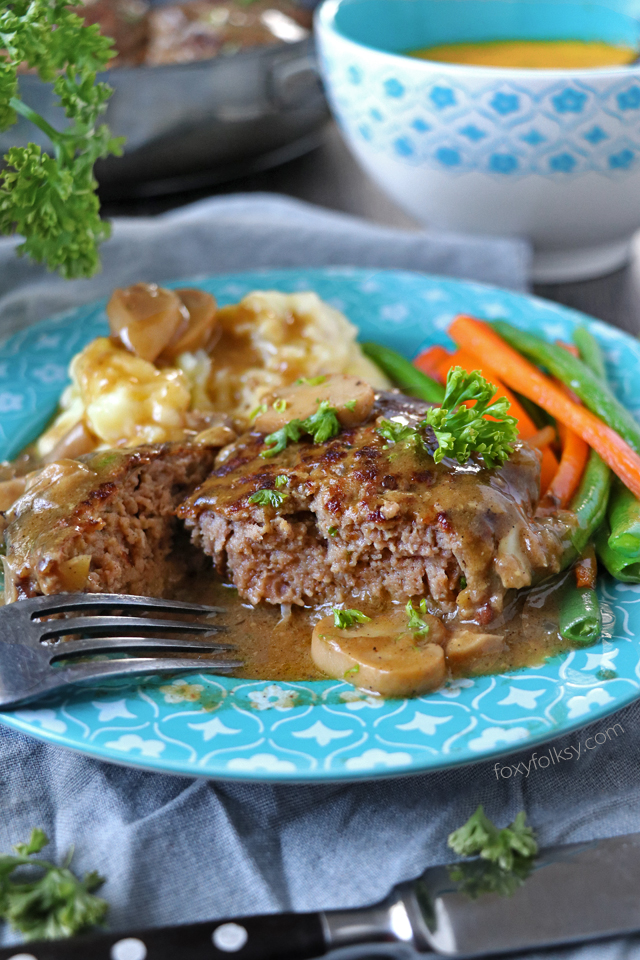 Try this simple Salisbury Steak recipe complete with Mushroom Gravy! So tender and juicy Steak patties swimming in thick tasty gravy! | www.foxyfolksy.com 