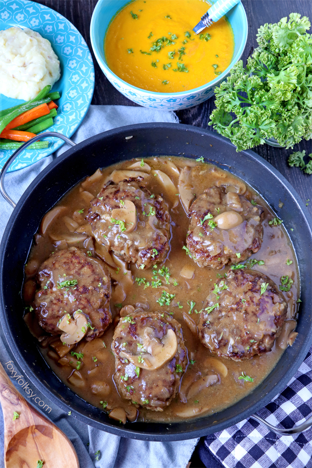 Try this simple Salisbury Steak recipe complete with Mushroom Gravy! So tender and juicy Steak patties swimming in thick tasty gravy! | www.foxyfolksy.com 