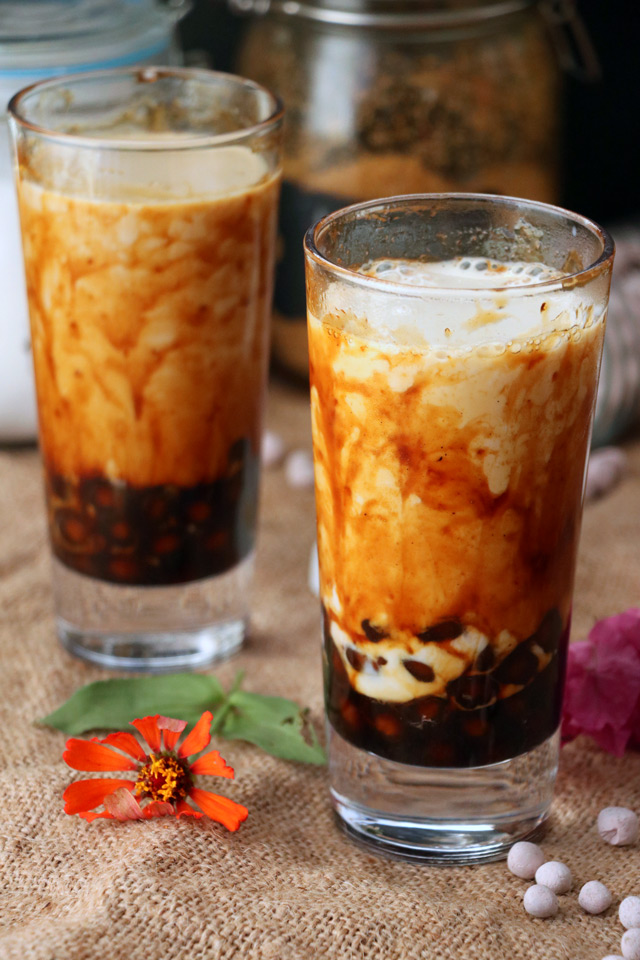 A picture of brown sugar milk tea; a drink with black boba at the bottom and a brown sugar syrup and milky drink mixed together.