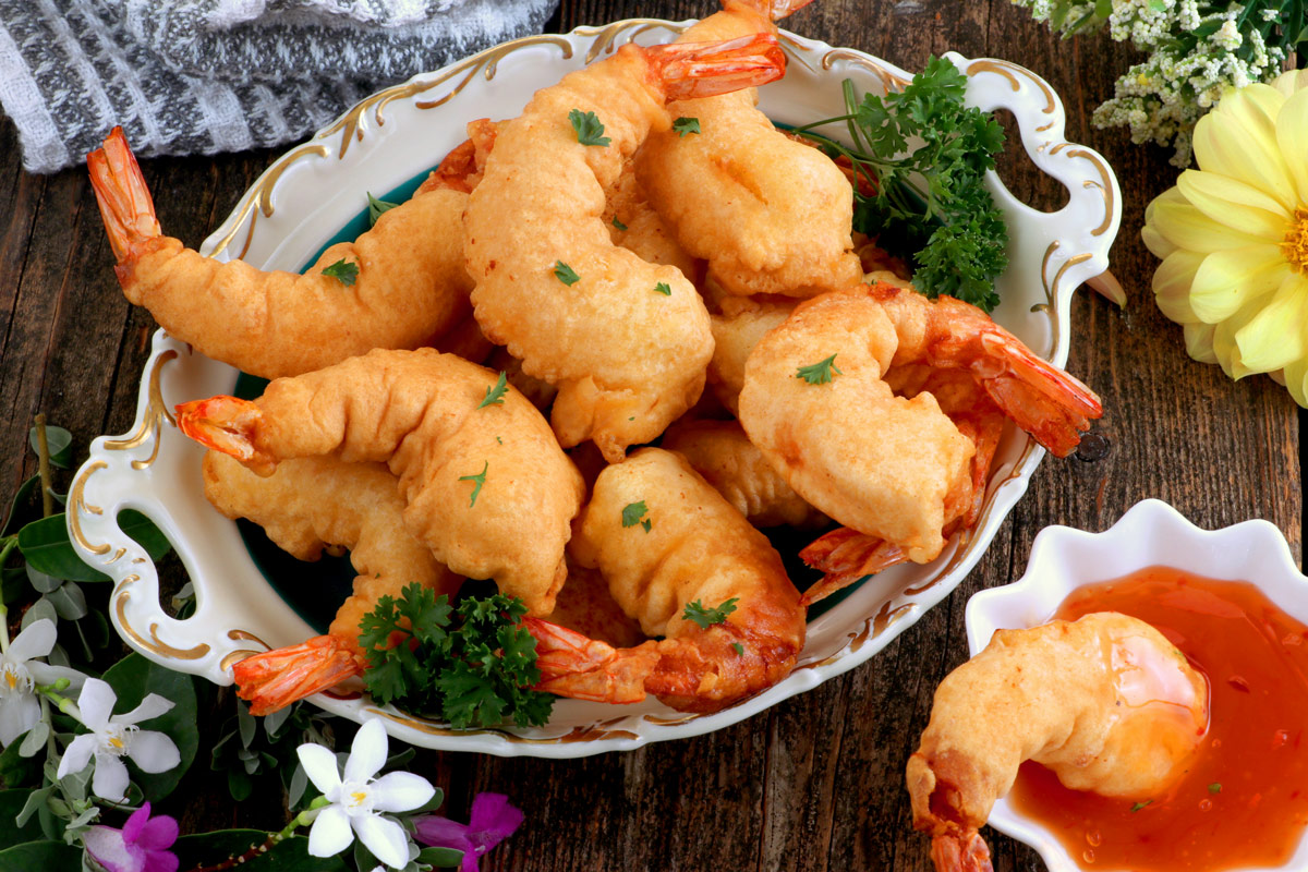 A plate full of fried battered shrimp.