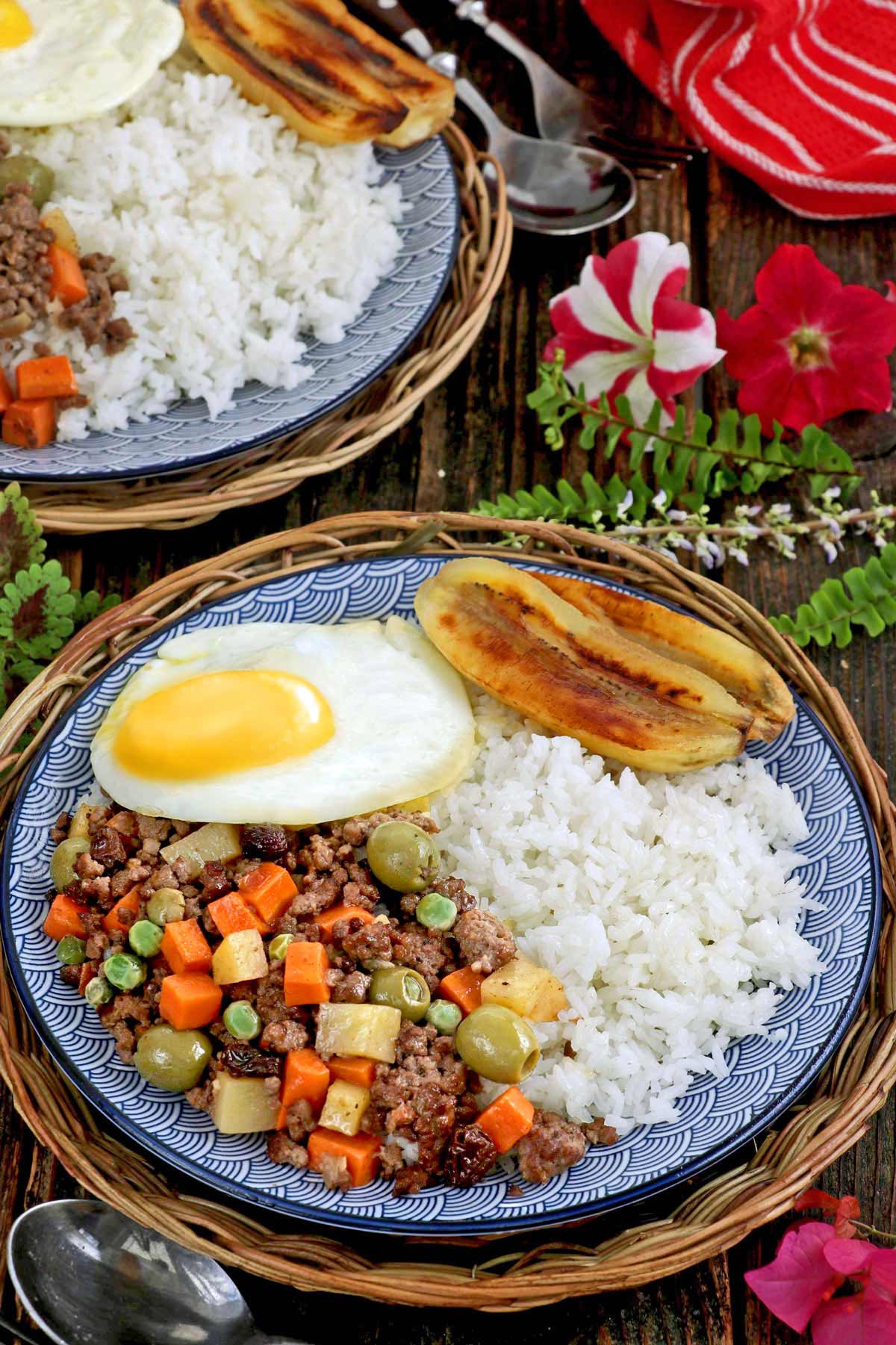 A plate of rice with cooked ground meat, fried egg and fried banana.