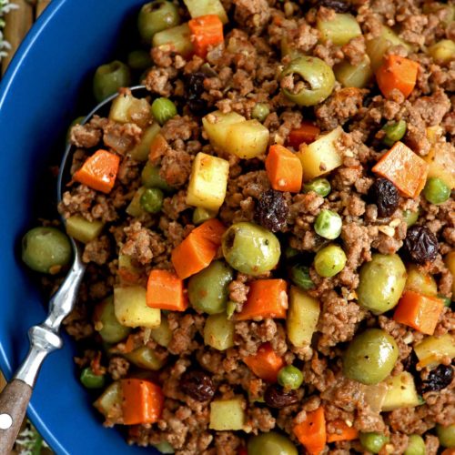 Picadillo recipe complete with ground beef, potatoes, carrots, olives, green peas, and raisins cooked in fresh tomatoes.