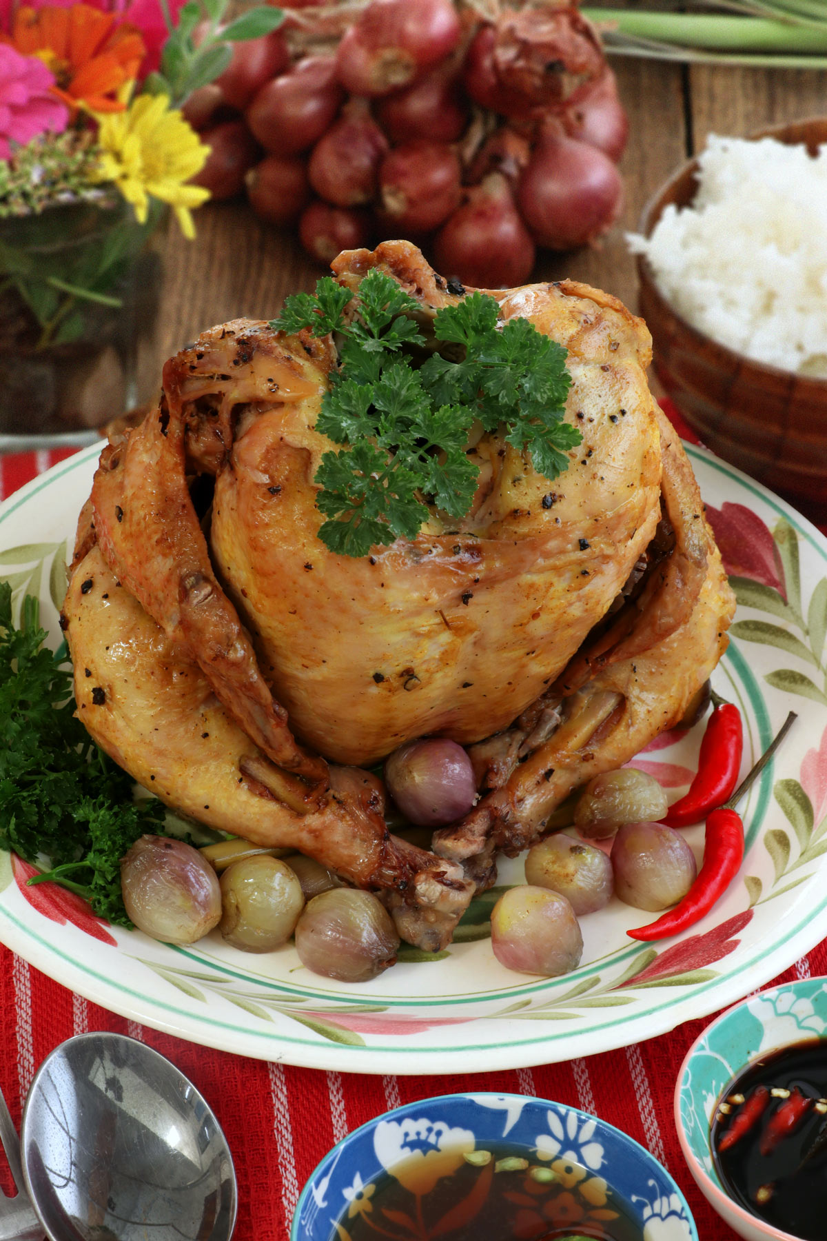 Whole chicken cooked upright on a bed of rock salt in a pot.