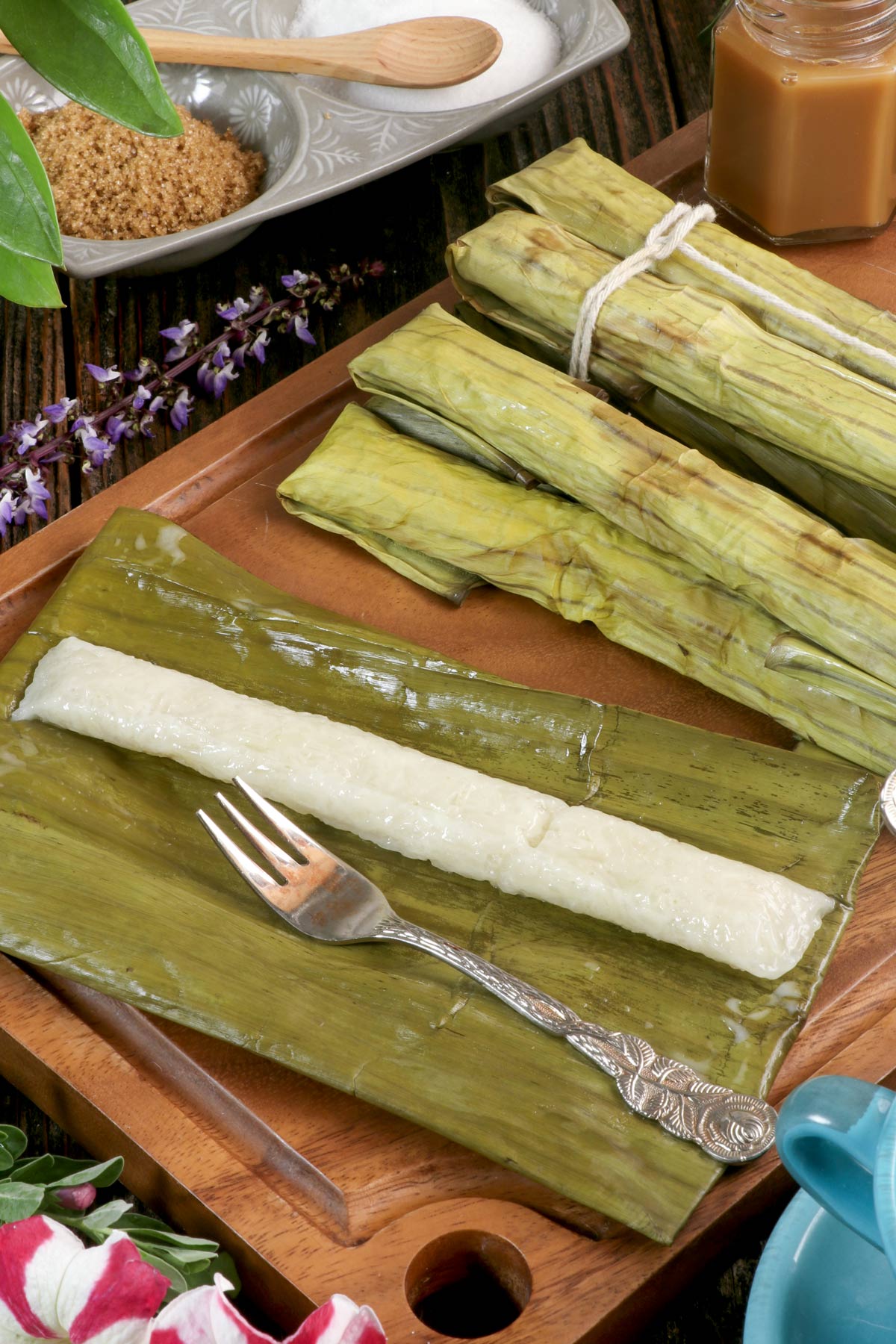 Freshly cooked Suman Malagkit on an unwrapped banana leaf served with a choice of sugar and caramel as dip.