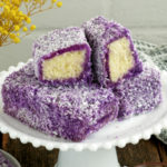 Cake bars dipped in ube glaze and coated with coconut flakes.