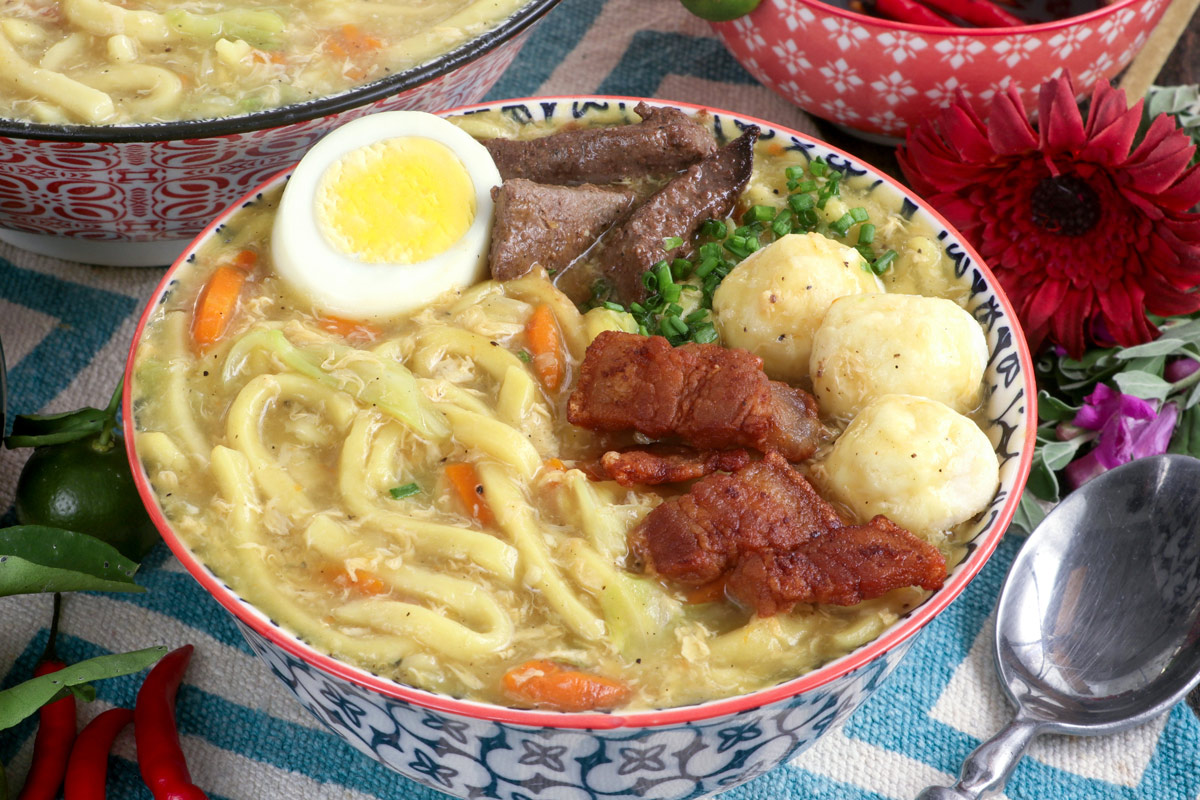 A hot bowl of Pancit Lomi with various flavorful toppings.