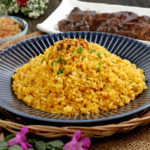Java rice on a plate with grilled meat and atchara on the side.