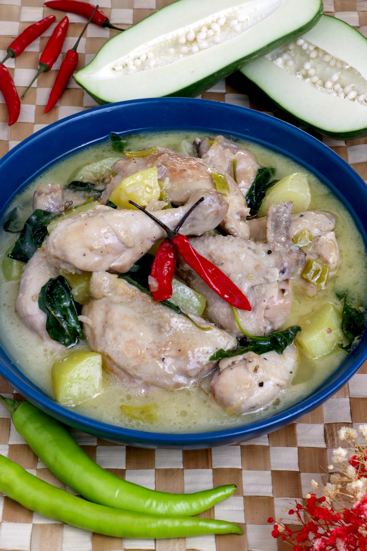 Chicken Halang halang in a serving bowl with chunks of tender green papaya and chili leaves in a creamy soup.