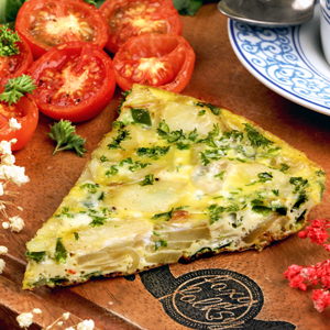 Sliced Potato Frittata made from golden brown potato slices, crisp green peppers, and sweet caramelized onions with a soft egg base and topped with parsley.