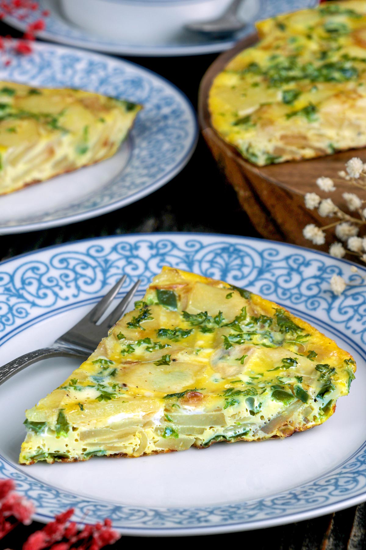 Healthy Potato Frittata made from golden brown potato slices, crisp green peppers, and sweet caramelized onions with a soft egg base and topped with parsley.