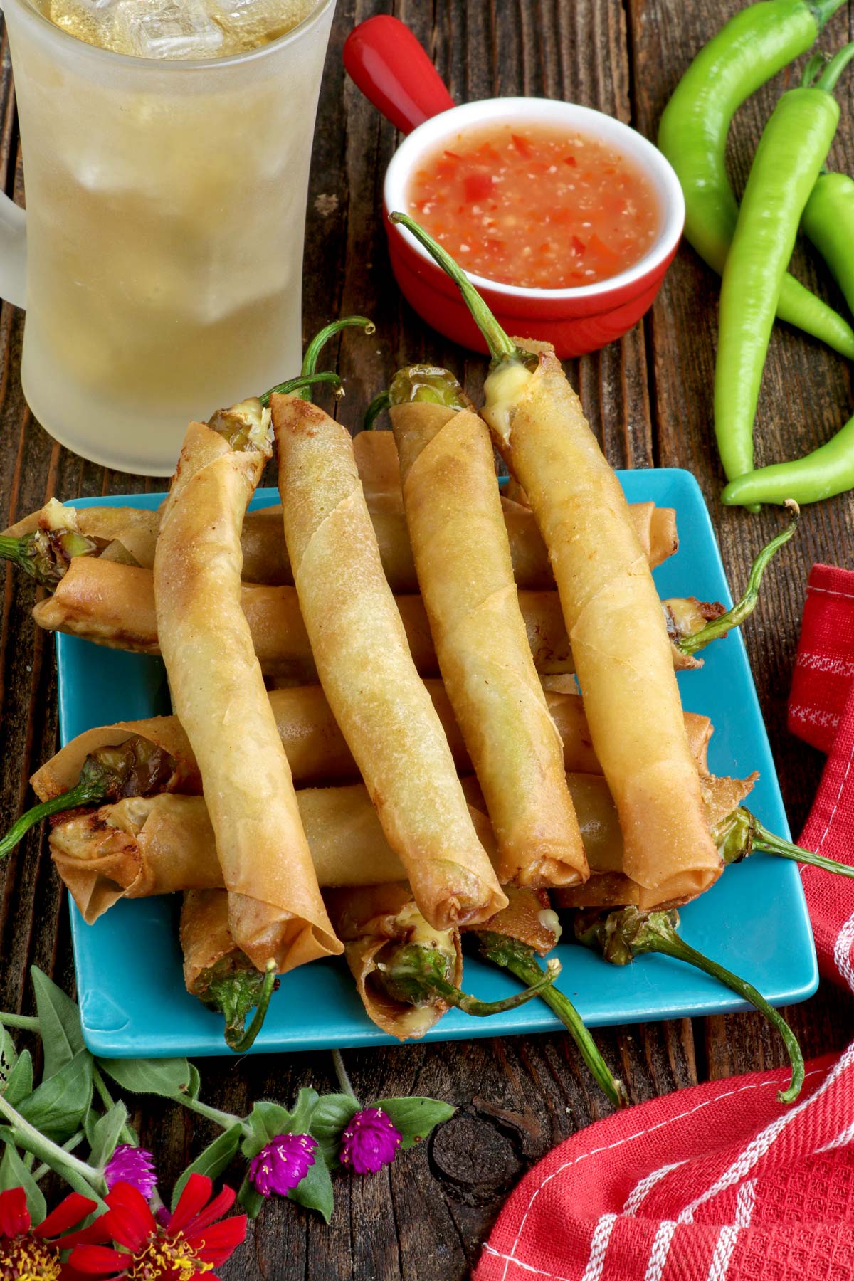 Cheesy Dynamite Lumpia on a serving plate with sweet and sour dipping sauce.