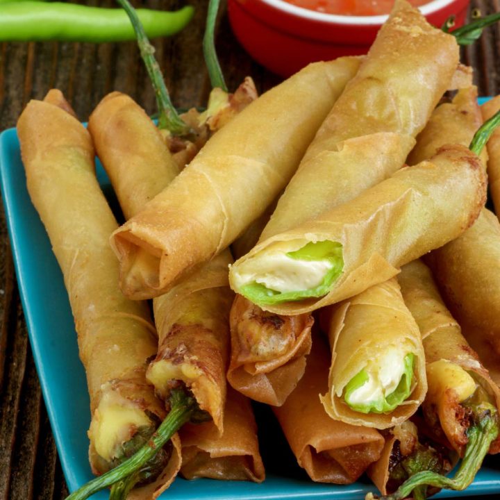 Dynamite Lumpia on a serving plate with sweet and sour sauce on the side.