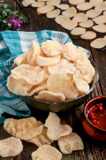 Crunchy and flavorful homemade Prawn crackers on a serving bowl with spiced vinegar on the side.