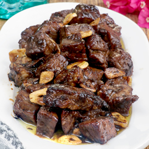 Beef Salpicao with toasted garlic bits on a serving plate with garlic rice.