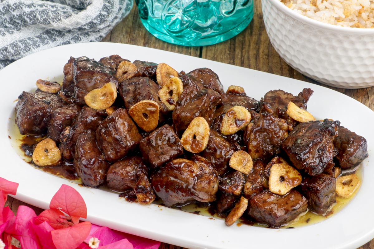 Beef Salpicao with toasted garlic bits on a serving plate with garlic rice.