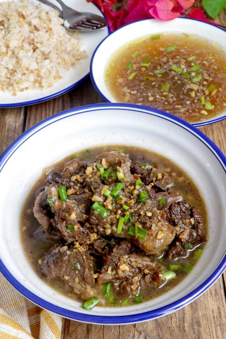 Beef Pares in a serving bowl with fried rice and beef broth on the side.