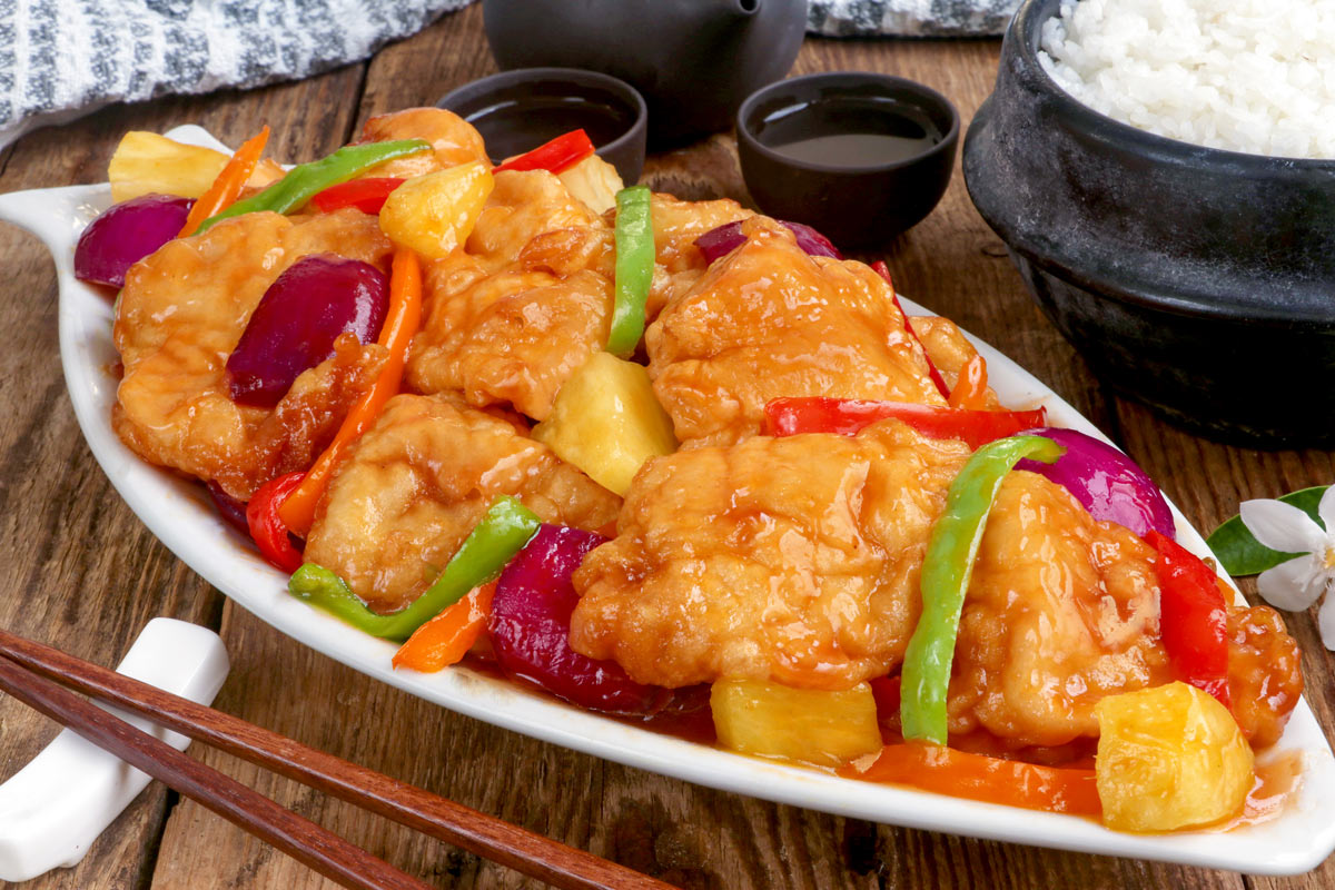 Freshly cooked sweet and sour fish fillet on a serving platter with steamed rice on the side,