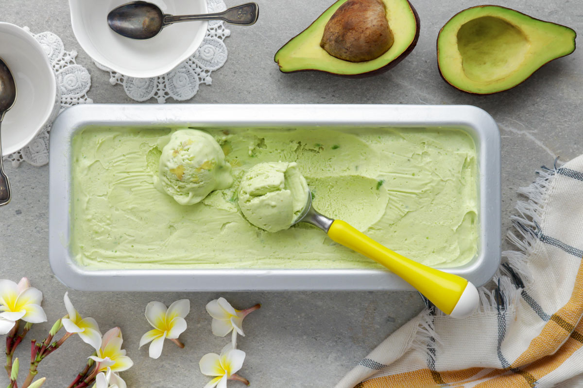 Avocado Ice Cream in a loaf pan with an ice cream scoop on top.