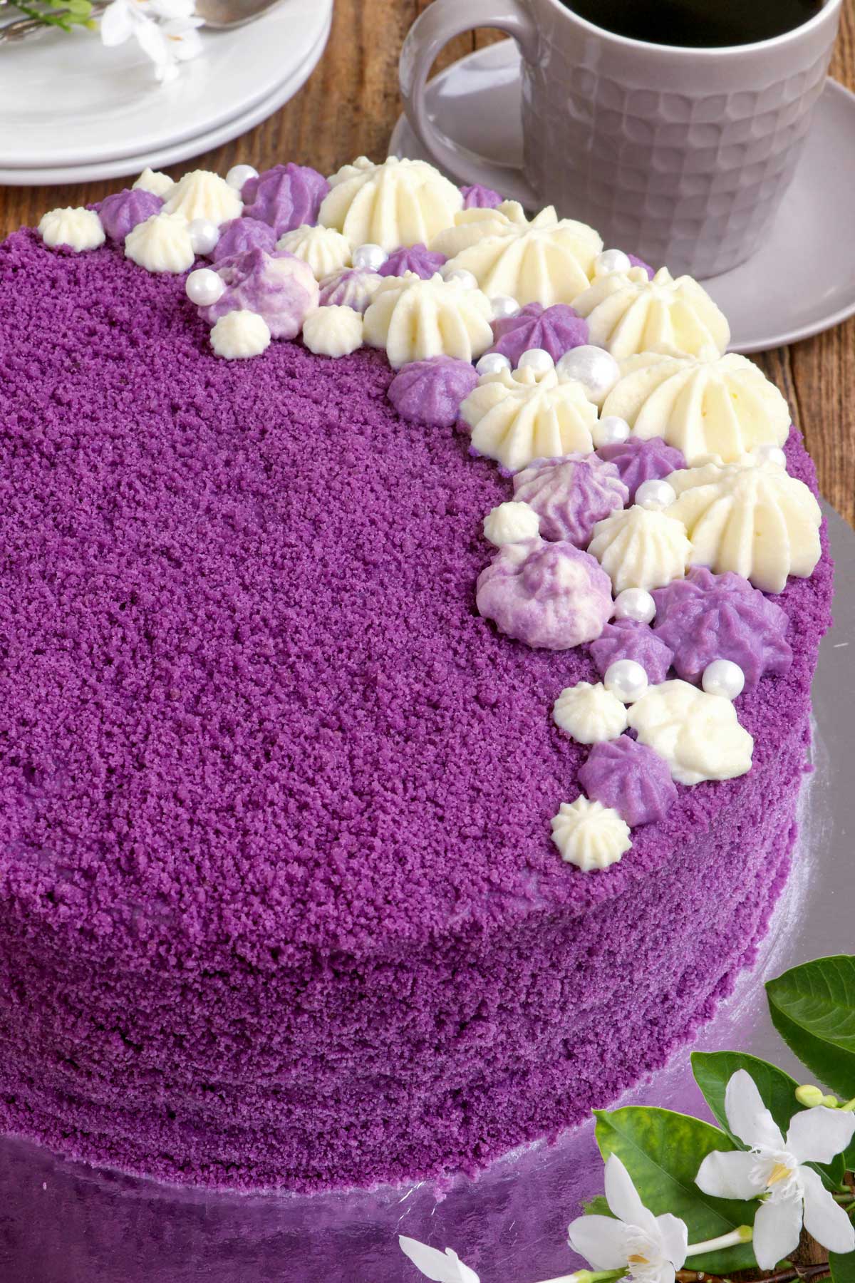 Purple Yam Cake with covered with ube-flavored cream cheese frosting and crumbs, on a serving plate.