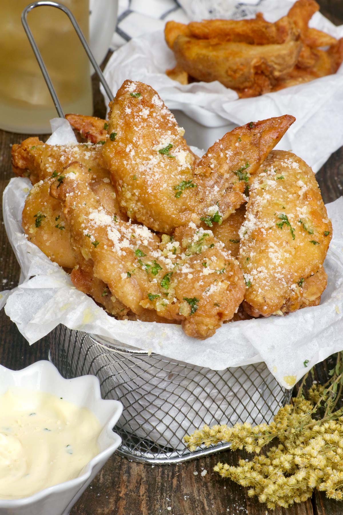 Crispy Garlic Parmesan Chicken Wings served with beer, dipping sauce, and potato wedges.