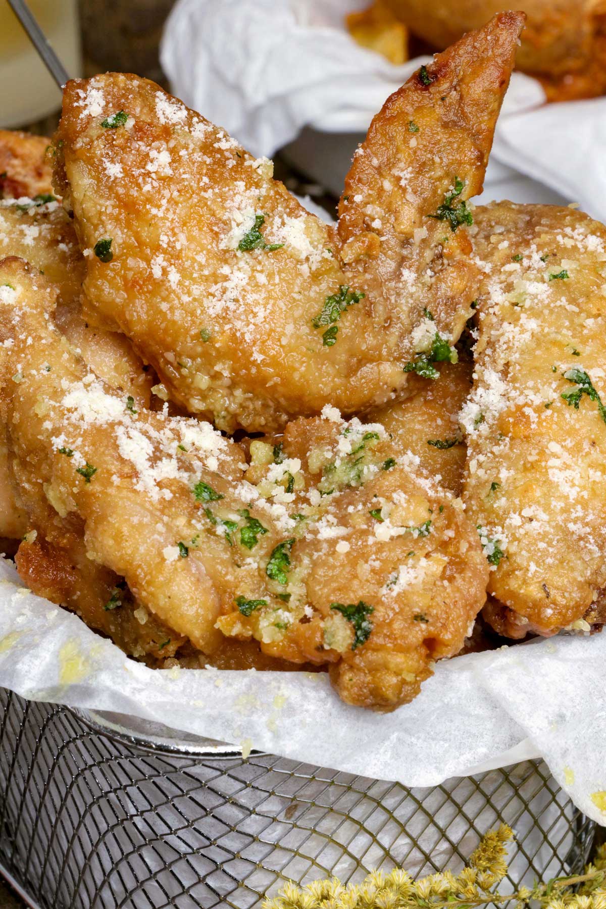 Garlic Parmesan Chicken Wings on a serving dish garnished with extra parmesan and chopped parsley.