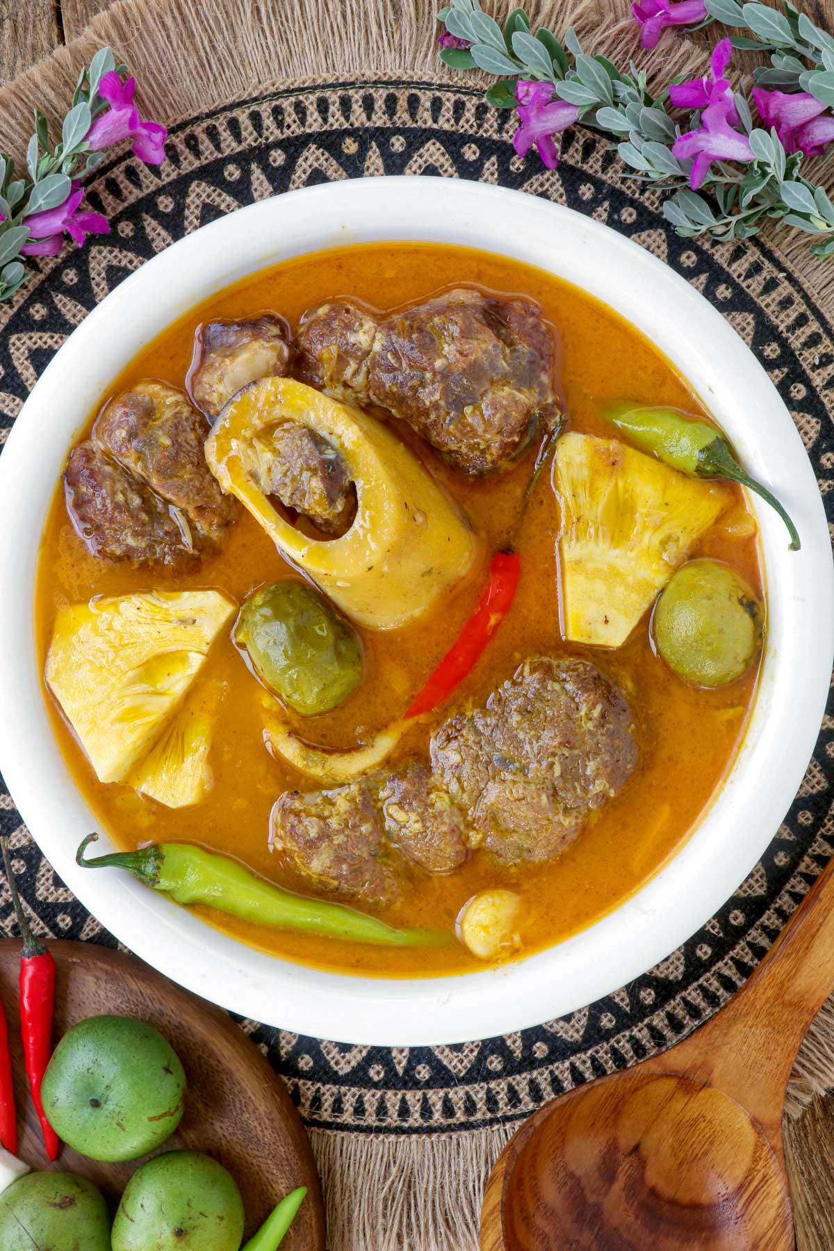 Kansi in a serving bowl made with beef shanks, green jackfruit, batwan, and chilis.