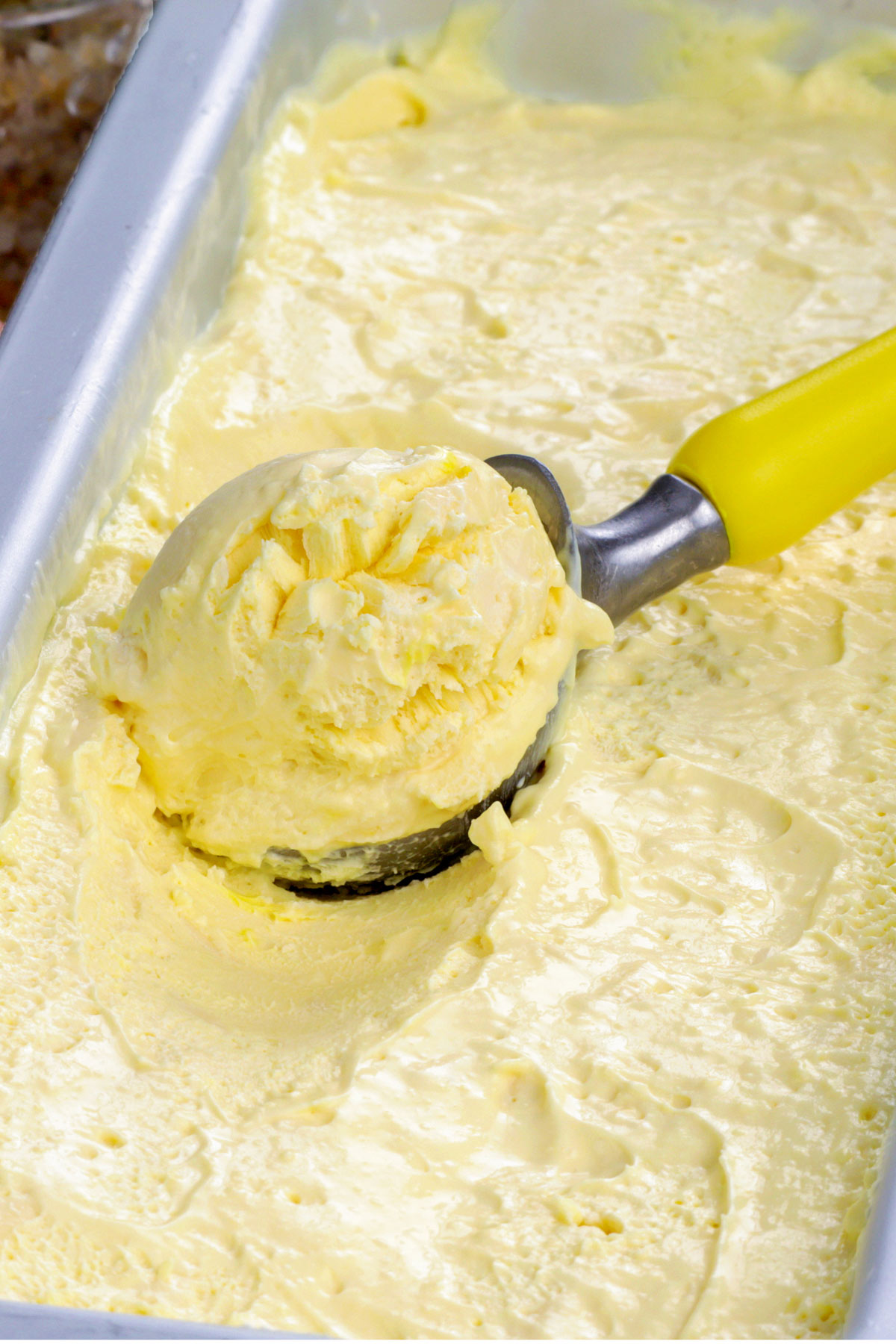 Frozen cheese ice cream on a container with an ice cream scoop.