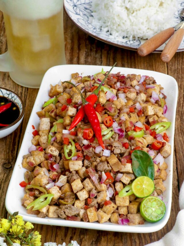 Tofu Sisig on a serving plate with sliced calamansi and red chili served with rice and cold beer.