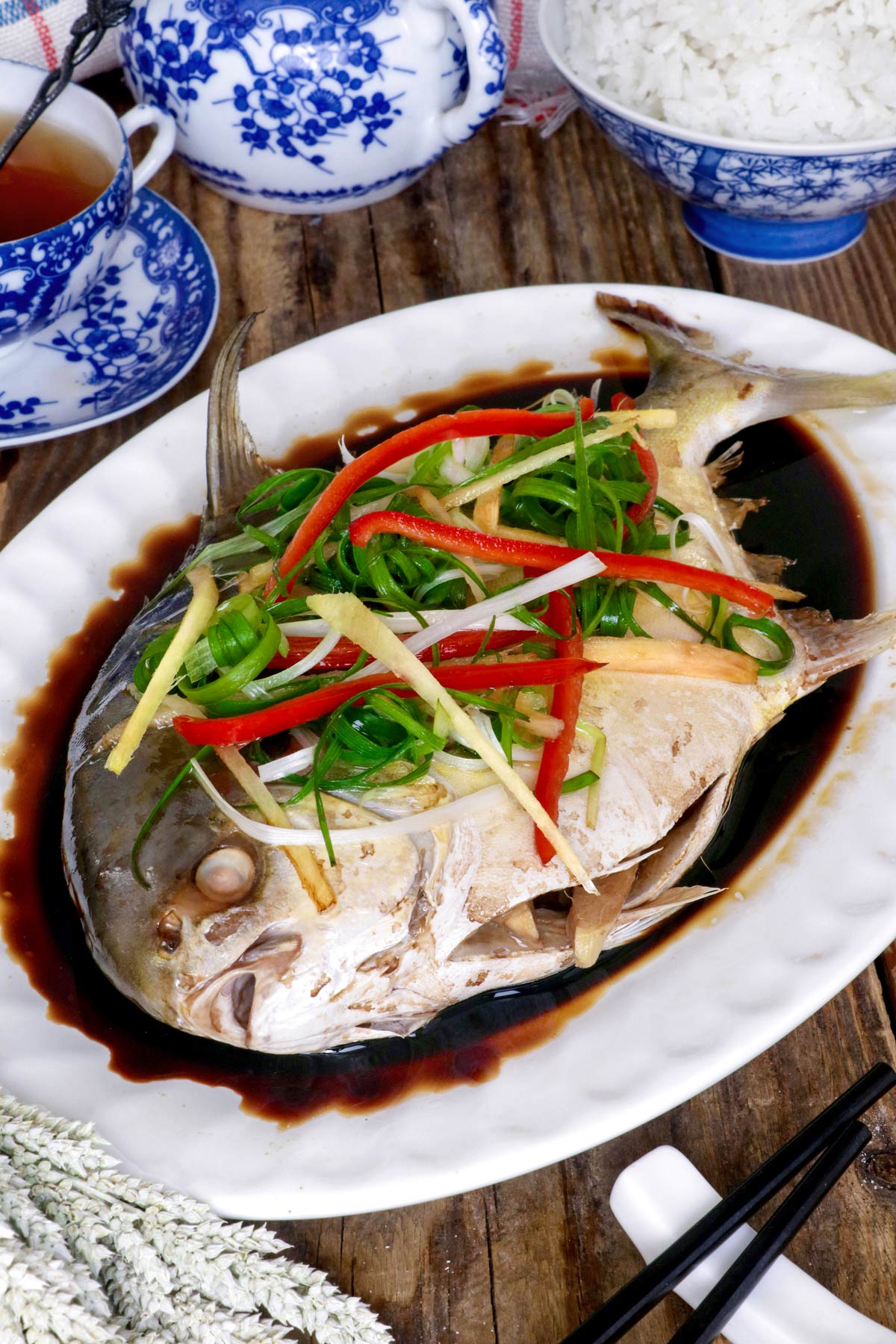 Whole steamed fish cooked Chinese style with soy sauce-wine mixture sauce in a serving platter.