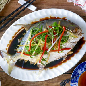 Whole steamed fish cooked Chinese style with soy sauce-wine sauce in a serving platter.