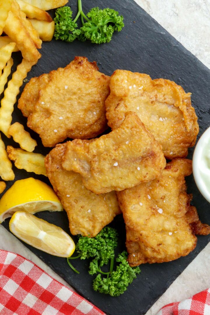 Crispy beer battered fish served with fries and lemon wedges.