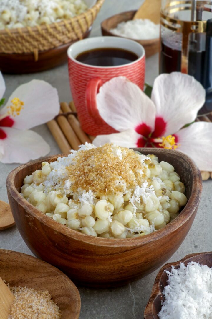 Binatog in a bowl topped with grated mature coconut and brown sugar.