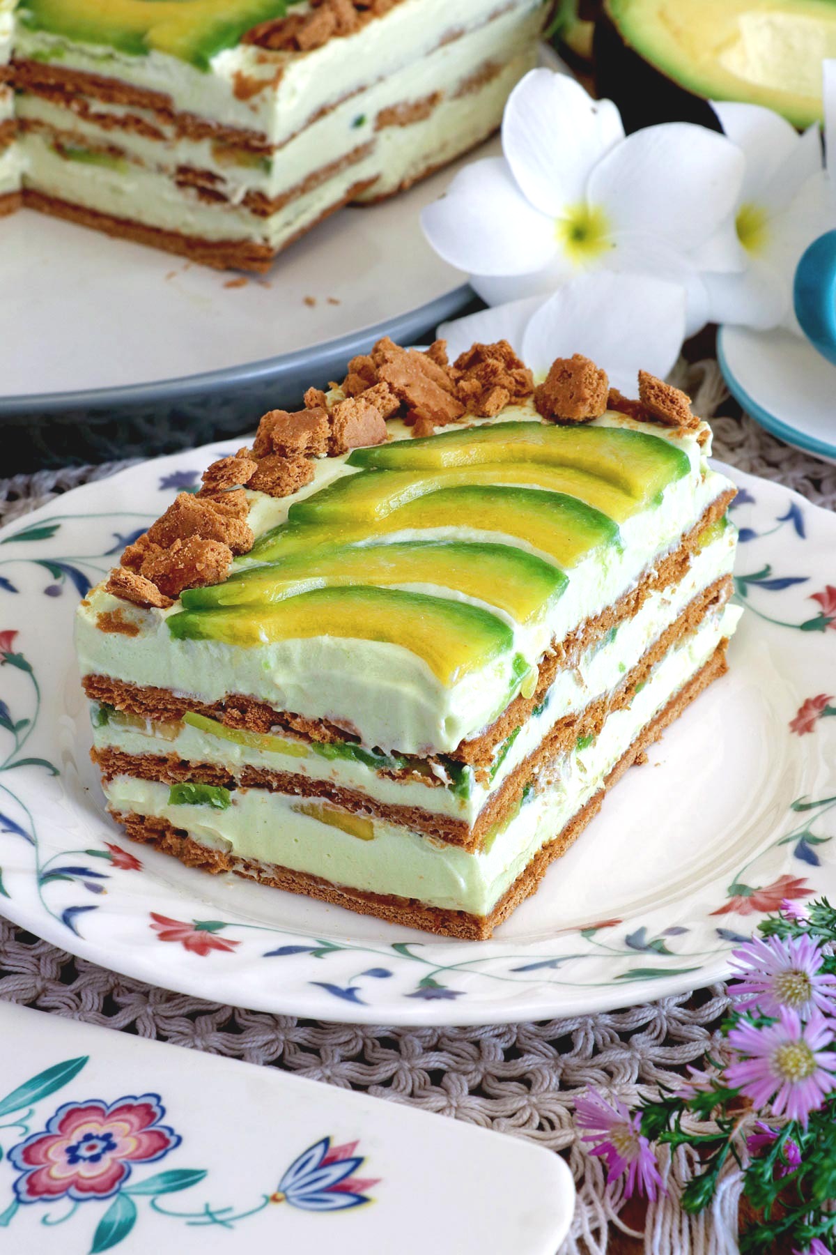Slices of avocado float topped with slices of avocado and crushed graham crackers in serving plates.