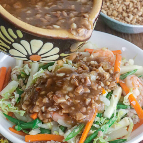 Lumpiang hubad in a serving plate being drizzled with the rich, nutty lumpia sauce.