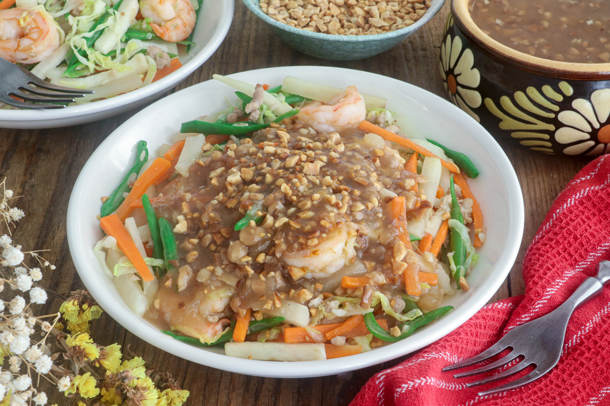 Lumpiang hubad in a serving plate topped with lumpia sauce and garnished with ground peanut.