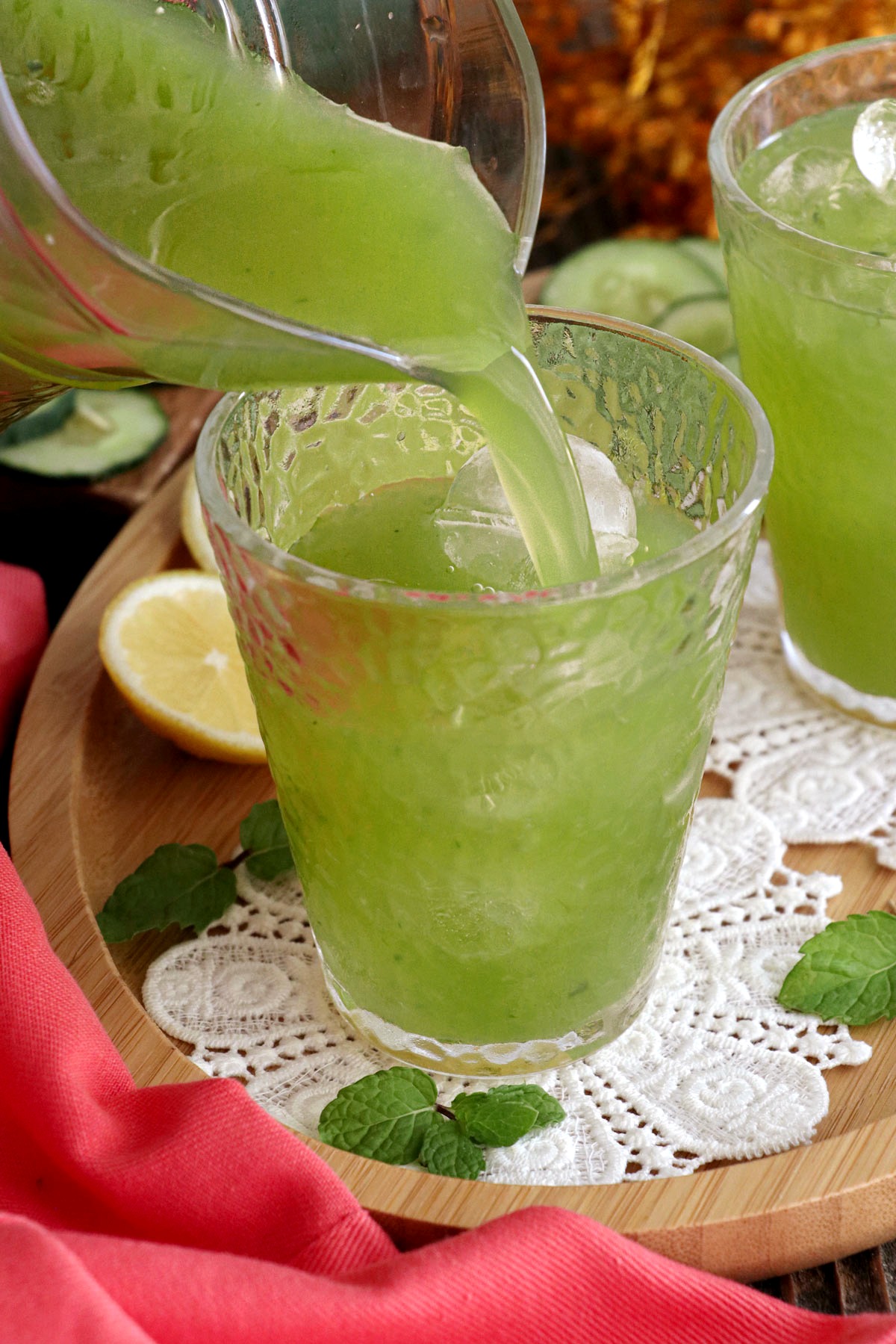 Cucumber juice being poured in a glass over ice.