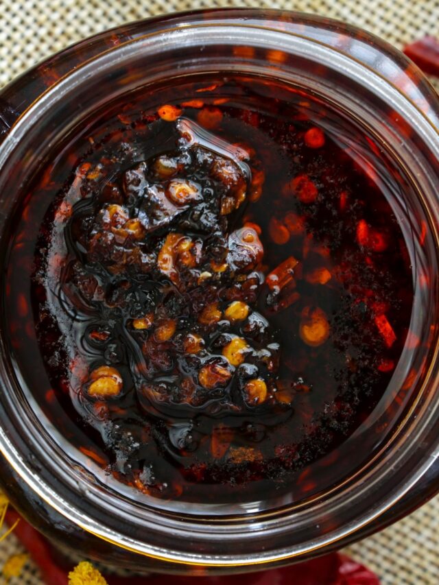 Chili oil in jars with dried chilis on the side.