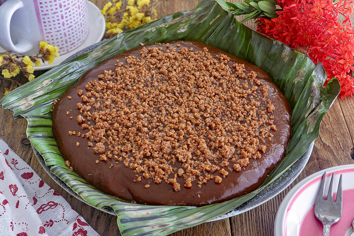 Kalamay Hati topped with latik in a serving platter lined with banana leaves.