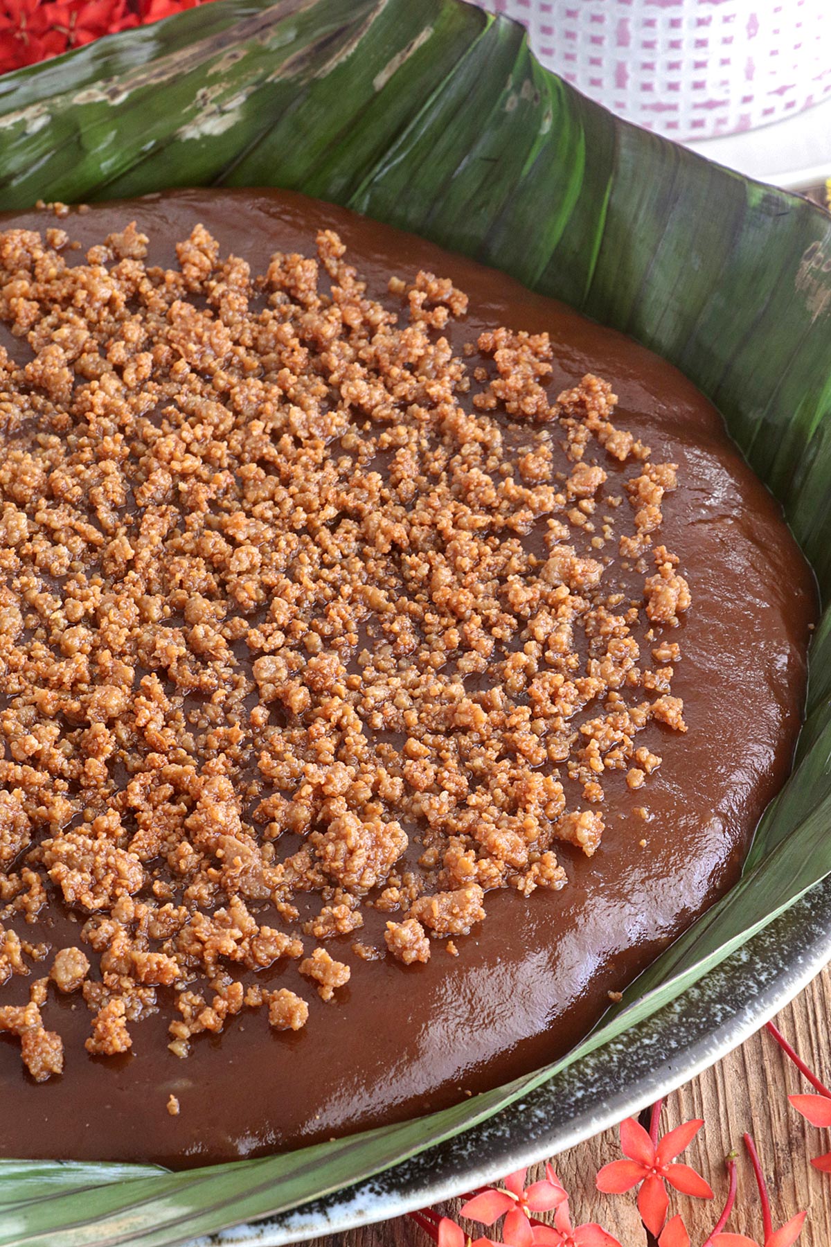 Kalamay Hati topped with latik in a serving platter lined with banana leaves.