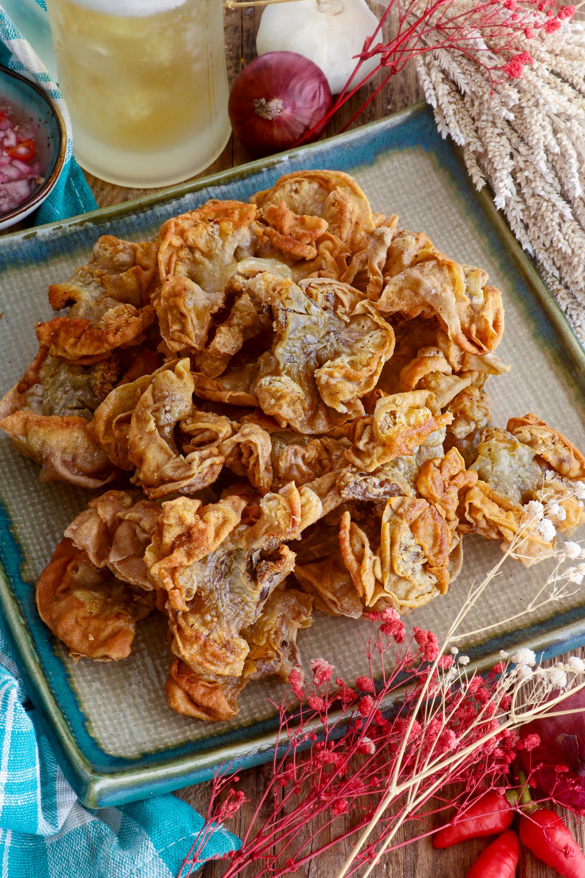 Chicharon bulaklak on a serving plate served with ice-cold beer and spiced vinegar dipping sauce.