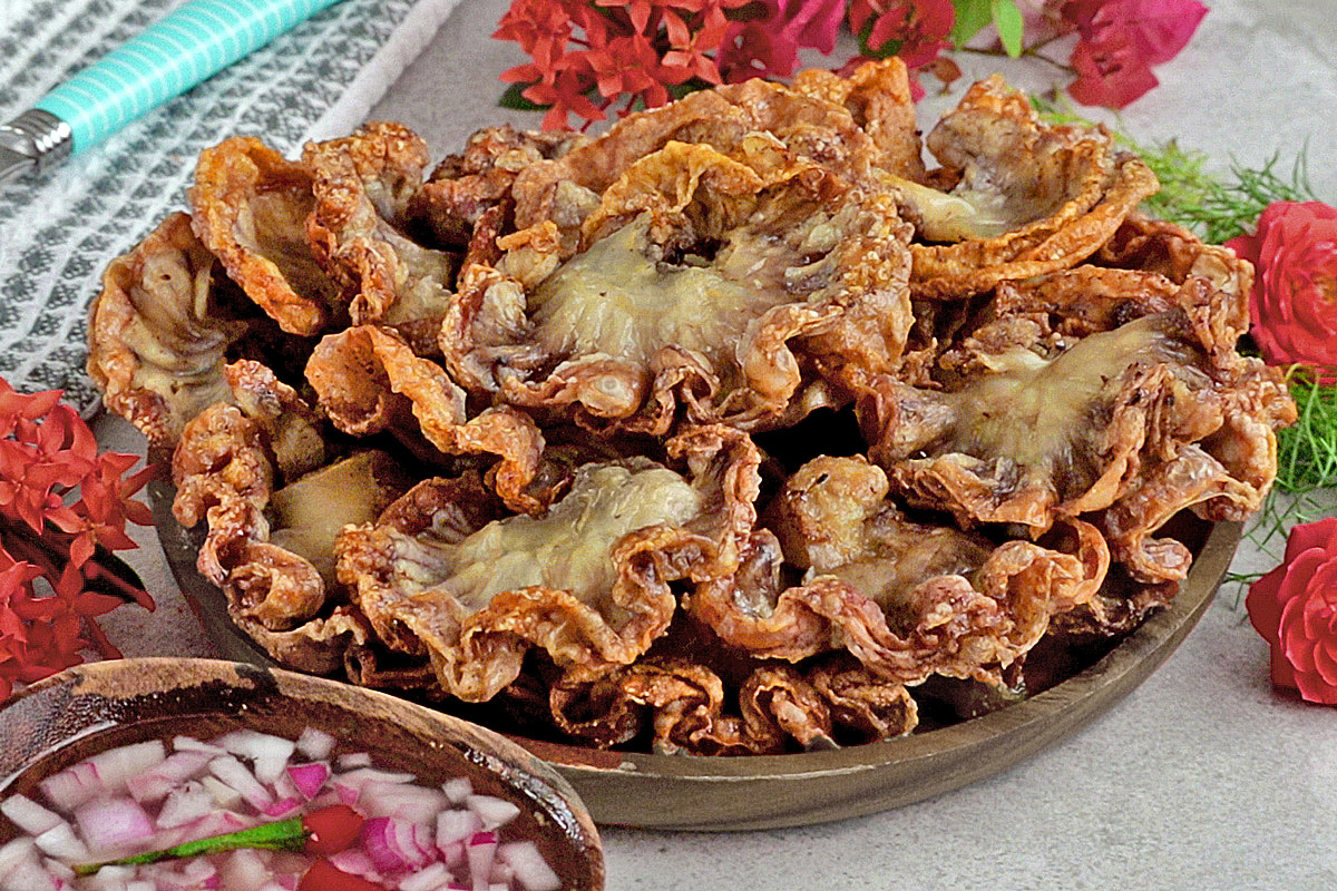 Chicharon bulaklak on a serving plate served with spiced vinegar dipping sauce.